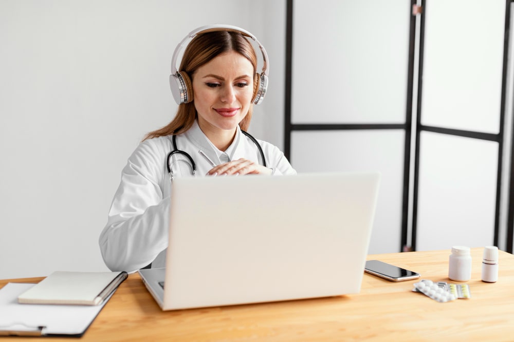 Médecin avec casque audio effectuant une téléconsultation sur ordinateur portable, illustrant la collaboration avec un service de télésecrétariat médical